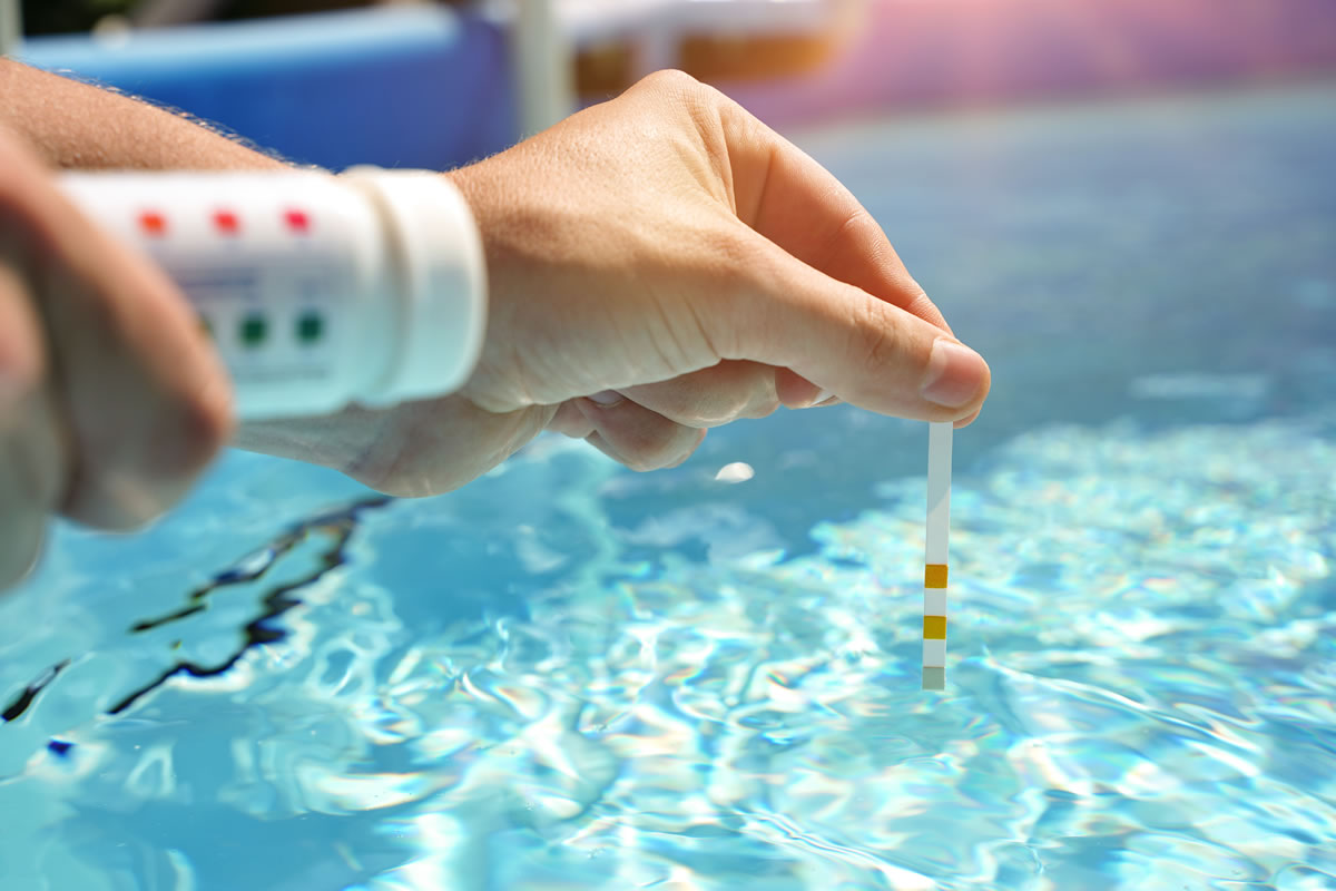 Technician testing swimming pool pH using test strips