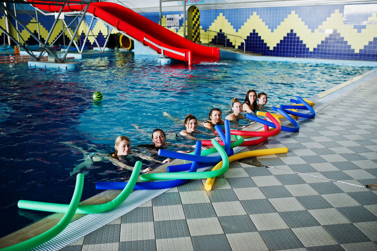 Group of women using swimming pool fitted with water slide Group of women using swimming pool fitted with water slide