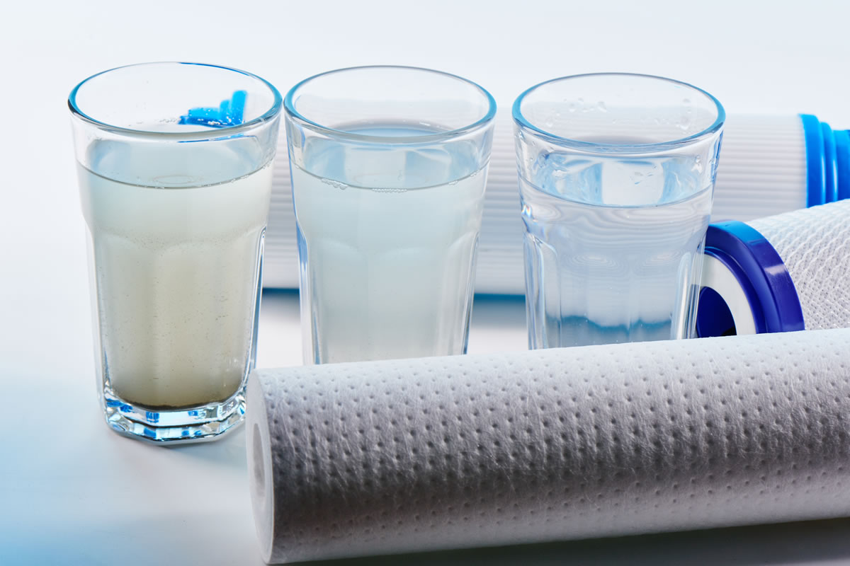 Three glasses of water, unfiltered to filtered, alongside reverse osmosis filters